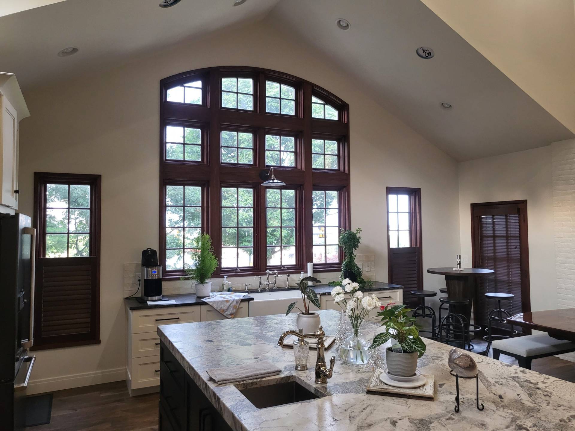 Custom kitchen with cathedral ceiling and granite countertop over white cabinets. Large arched windows with natural burgundy trim fill the wall. Designed by Brad M. Zahm, RA, NCARB and The Mula Group