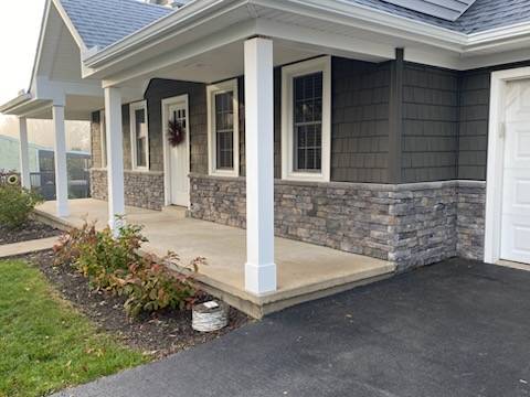 Angled view of porch highlighting the new posts, vinyl shake siding, and dry stacked stone wrapped around the side to the garage.