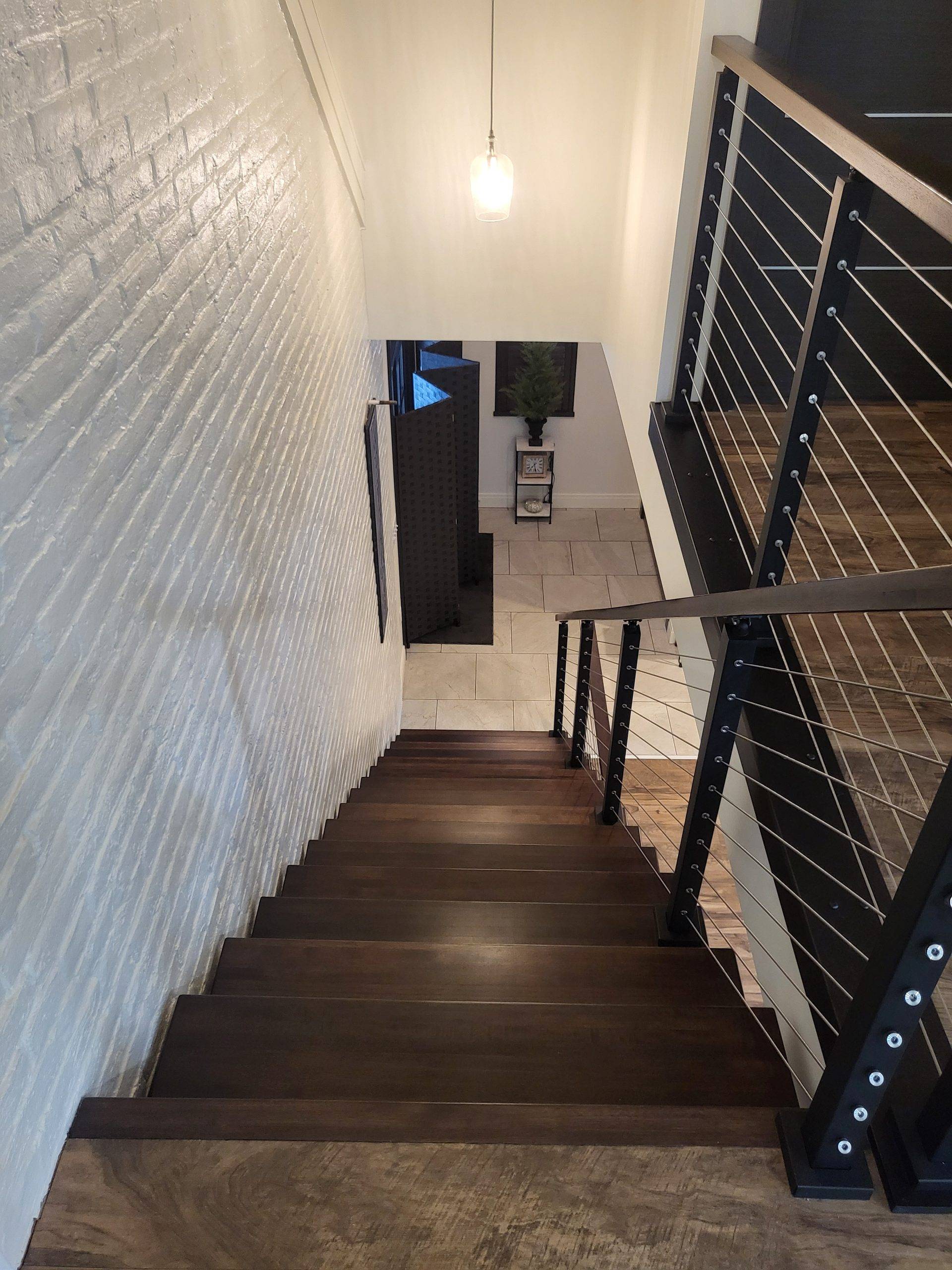 View from second floor down custom floating tread staircase with cable and steel railing and banisters to new entryway. Designed by Brad M. Zahm, RA, NCARB and The Mula Group.