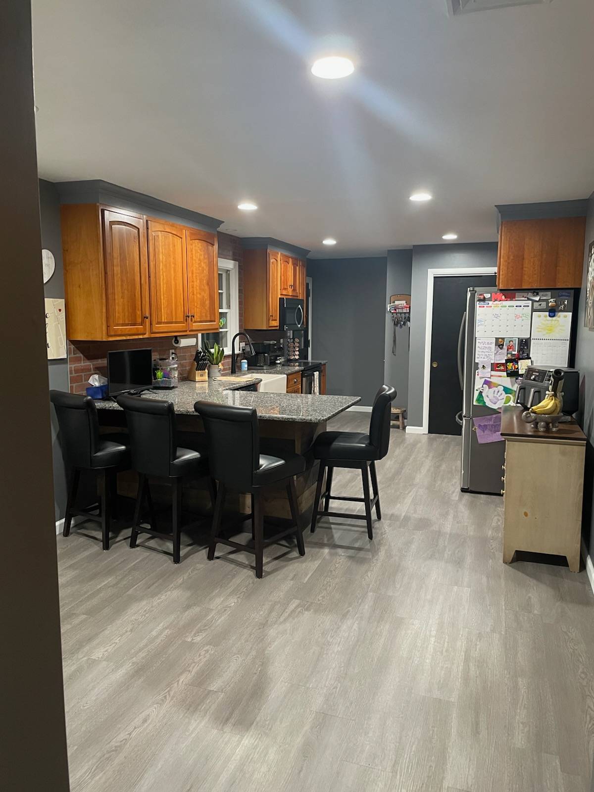 Renovated kitchen with custom peninsula, new cabinets, backsplash, flooring, and ceiling with recessed lighting.