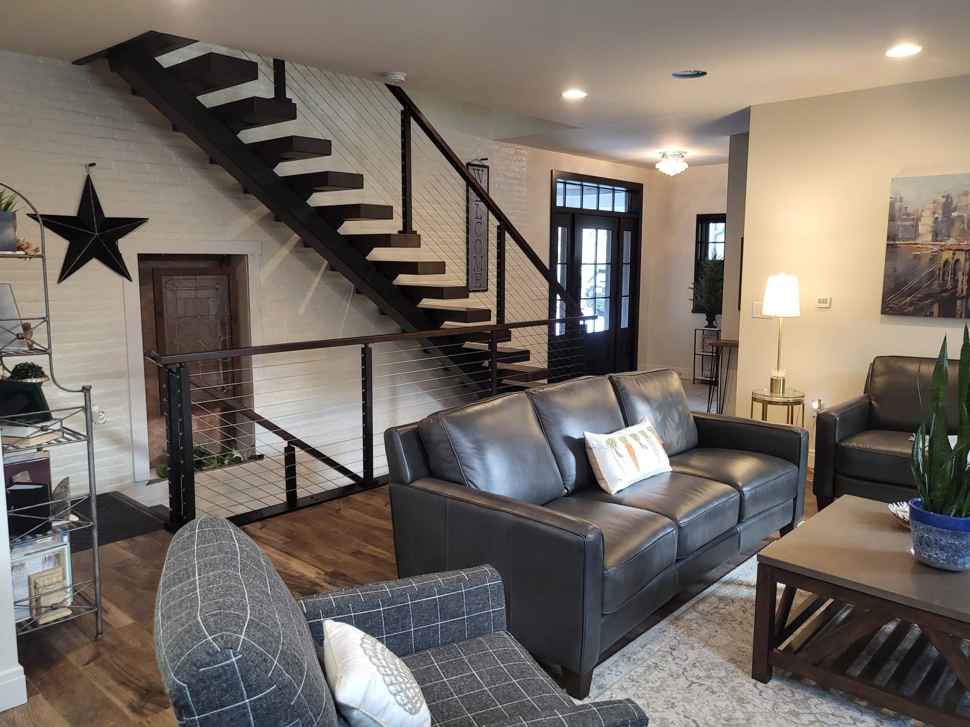 Living room with custom floating tread stairs and cable railing leading to second floor library and owner's suite. Designed by Brad M. Zahm, RA, NCARB and The Mula Group.