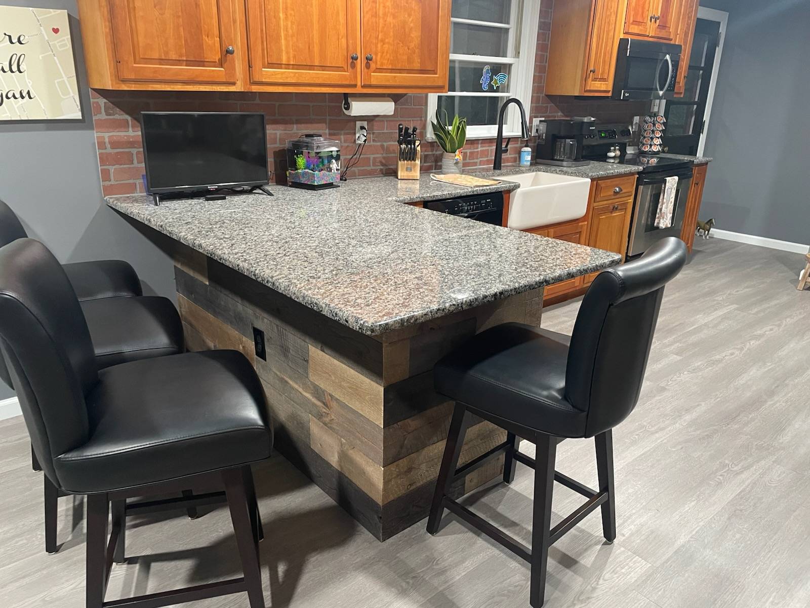 Close up of renovated kitchen's peninsula base. Farmhouse sink and granite countertops highlight the new cabinetry.